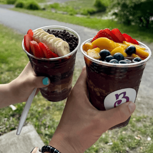 Two people holding TurnBerry acai bowls
